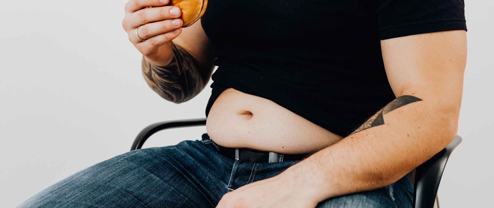 man with cheeseburger showing belly