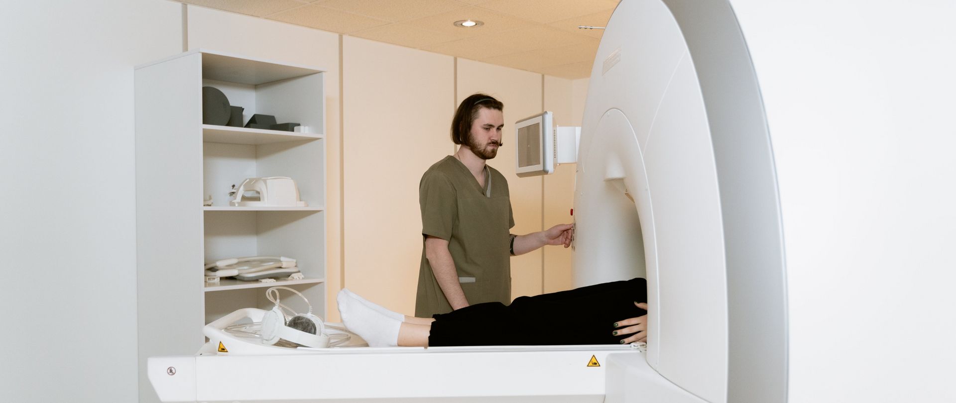 tech next to patient in CT scanner